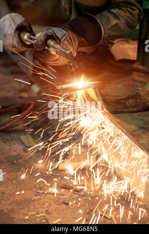 Lavoratore in fabbrica di taglio della piastra in acciaio utilizzando gas torcia in metallo. Foto Stock