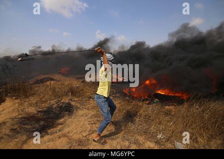 La striscia di Gaza. 27 apr, 2018. Un manifestante palestinese utilizza un slingshot a scaglia pietre alle truppe israeliane durante gli scontri sul confine Gaza-Israel, a est di Khan Younis City, nel sud della striscia di Gaza, il 27 aprile 2018. Credito: Khaled Omar/Xinhua/Alamy Live News Foto Stock