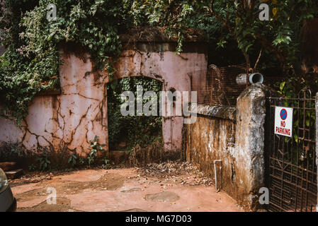 Una rosa adobe archway con infittimento e piante in una giornata di sole in Goa, India Foto Stock