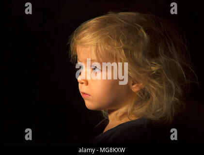 Una chiave di basso studio bambino ritratto di una giovane e bella ragazza Foto Stock