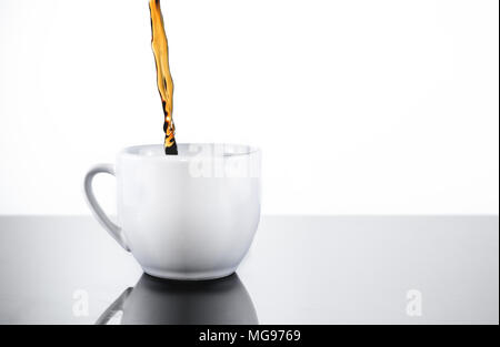 Riempimento di un colore bianco porcellana mug cup con fresco, buio nero caffè o tè Foto Stock