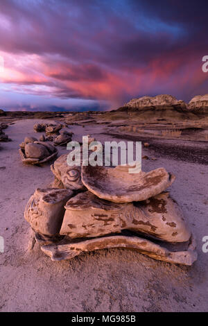 Bisti o De-Na-Zin Wilderness Area o formazioni rocciose di badlands al tramonto con nubi tempesta sullo sfondo, New Mexico, USA Foto Stock