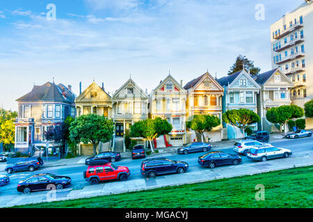 SAN FRANCISCO, 1 APR, 2018: tardo pomeriggio di sole illumina una fila di colorate case in stile vittoriano noto come Painted Ladies attraverso da Alamo Square. Costruito scommessa Foto Stock