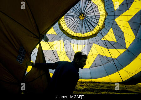 Silhouette di un crewman all'interno di un gonfiaggio retroilluminato in mongolfiera ad aria calda Foto Stock