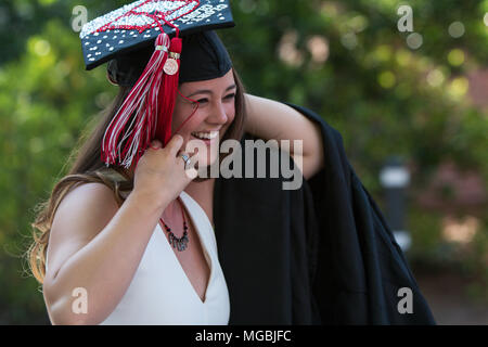 Un sorridente laureato femmina si prepara a mettere su la sua laurea robe come lei cammina verso la UGA cerimonia avvenuta il 13 maggio 2016 ad Atene, GA. Foto Stock