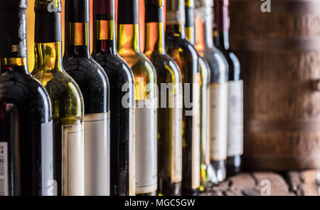 Le bottiglie di vino in fila e rovere barile di vino. Foto Stock