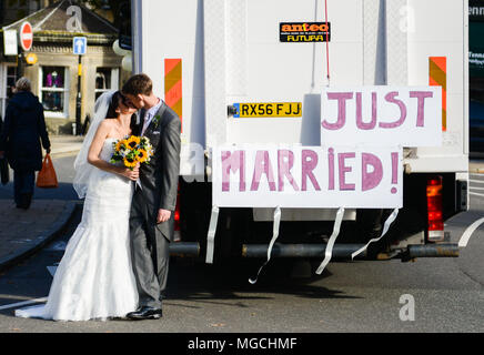 Coppia di novelli sposi kissing, accanto al carrello con grande 'Just Married " segno attaccato alla parte posteriore Foto Stock