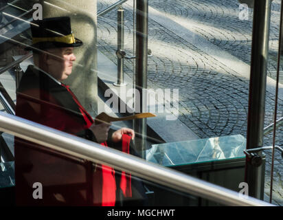 Portiere con top hat mettere mano su appendiabiti, visto attraverso il vetro della finestra Foto Stock