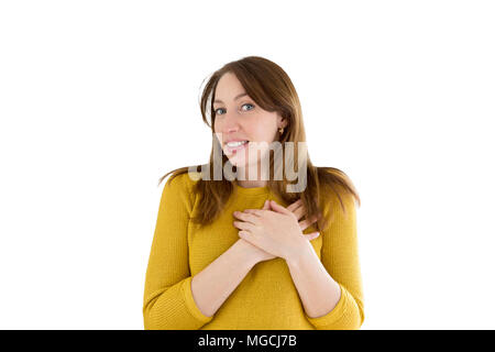 Felice giovane donna informale tenendo le sue mani dal suo cuore con emotiva naturali godendo la faccia. Il concetto di amore Foto Stock