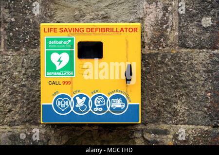 Colchester, Regno Unito - 12 Aprile 2018: una vita Risparmio defibrillatore per uso pubblico in caso di emergenza, appeso a una parete di pietra . Foto Stock