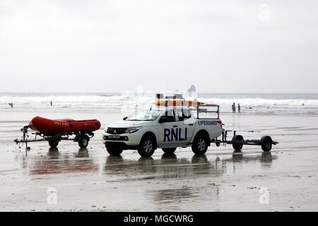 Perranporth, Cornwall, Regno Unito - 9 Aprile 2018: carrello e gommone appartenenti al RNLI bagnino di salvataggio con il surf e le onde in background. Foto Stock