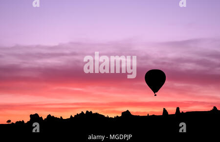 Mongolfiera in silhouette in montagne di sunrise, Goreme, Cappadocia, Turchia Foto Stock