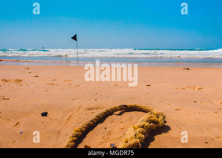 Black Flag di avviso che segna il limite della safe area nuoto su una bellissima spiaggia con cielo blu e un mare turchese in Israele. Foto Stock