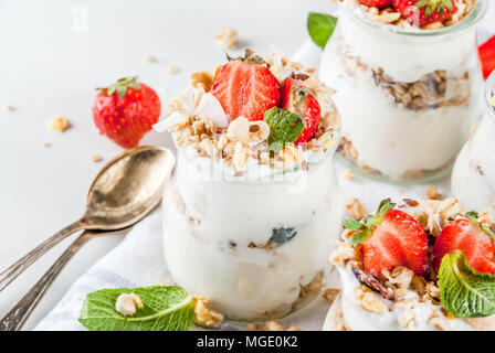 Una sana prima colazione estate idea, casalinghe parfe stratificata dessert in vaso piccolo con muesli, yogurt e fragola, sfondo scuro spazio copia Foto Stock