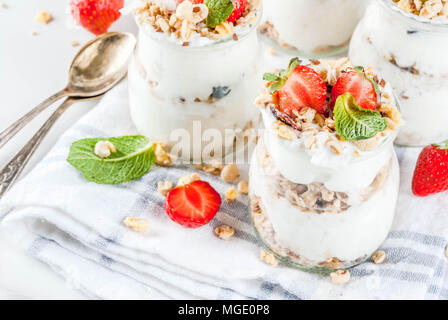 Una sana prima colazione estate idea, casalinghe parfe stratificata dessert in vaso piccolo con muesli, yogurt e fragola, sfondo scuro spazio copia Foto Stock