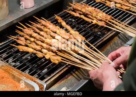 Spiedino di cinesi per la vendita di un prodotto alimentare in stallo Foto Stock