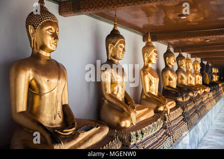 Oro statue di Buddha posto in una fila sotto un soffitto ornamentali, si trovano nel tempio di Wat Pho a Bangkok dove vi è anche una grande statua Foto Stock