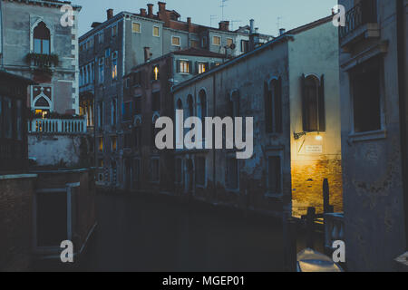 Vista di un canale di Venezia al tramonto, mentre la debole luce proveniente dalle lampade stradali inizia a illuminare l'acqua creando una sorta di effetto magico Foto Stock