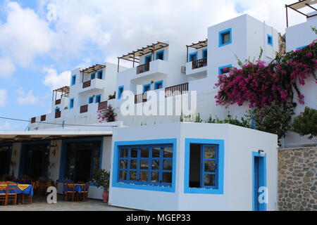 Tipico bianco e blu case greche con fiori viola che scendono dai balconi sull isola di Karpathos in Grecia nel Mare Mediterraneo Foto Stock