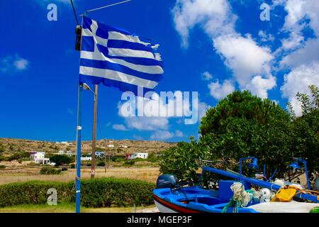 Bandiera Greca agitando in una giornata di sole con il cielo blu, il paesaggio della Grecia in background e un colorato di blu barca a fondo Foto Stock