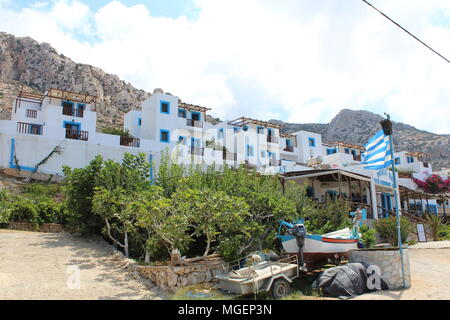 Tipico bianco e blu case greche con fiori viola che scendono dai balconi sull isola di Karpathos in Grecia nel Mare Mediterraneo Foto Stock