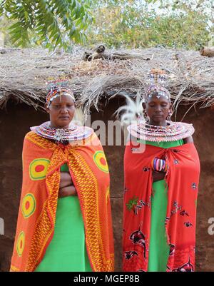 Masai donne che indossano colorati di verde e rosso abiti durante un rito tribale in un villaggio africano in Kenya, vicino a Nairobi Foto Stock