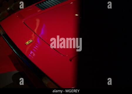 Grifo rosso di una Ferrari Testarossa che sporge dalla parete, con la ben illuminato logo Ferrari e la riflessione della luce sul cofano Foto Stock