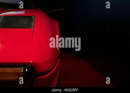 Grifo rosso di una Ferrari Testarossa che sporge dalla parete, con la ben illuminato logo Ferrari e la riflessione della luce sul cofano Foto Stock