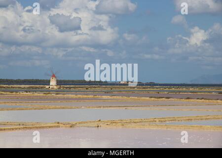 Un faro di bianco con un tetto rosso nel mezzo delle saline di Marsala in Sicilia, l'Italia, in una bella giornata di sole con un cielo blu che riflette Foto Stock