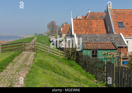 Case tradizionali lungo una diga in Makkum, storico villaggio olandese Foto Stock