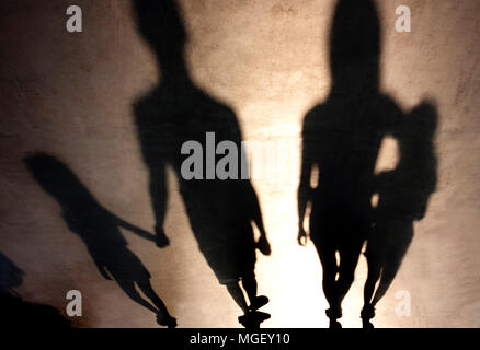 Ombre sfocate silhouetes della famiglia con figli che camminano mano nella mano e in un abbraccio in estate tramonto Foto Stock