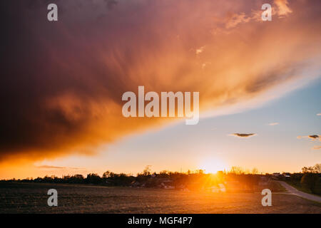 Tramonto primaverile Sunrise. Sun al di sopra di villaggio in campagna bielorussa. Luminoso cielo drammatico oltre il paesaggio di campagna dopo la pioggia. Sun su Skyline Horizo Foto Stock