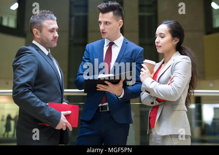 Grave bel giovane esperto aziendale in tuta blu che spiega la sua idea di squadra mentre si discute la strategia per lo sviluppo del business Foto Stock