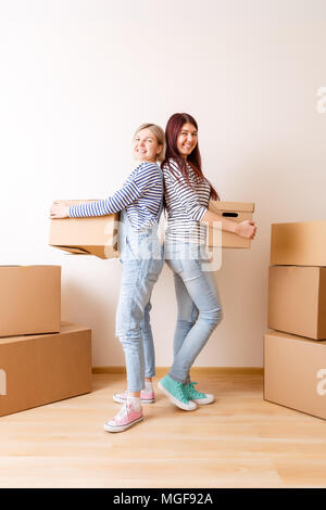 Foto di due donne in piedi tra le scatole di cartone Foto Stock