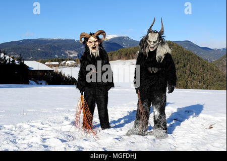 Due Krampus figure nella campagna vicino alla città di Castelrotto (Castelrotto), Alto Adige, Italia Foto Stock