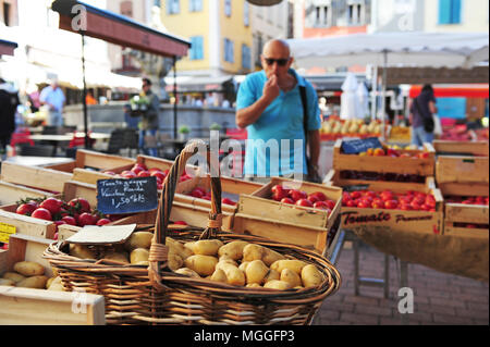 Uomo che guarda uno di frutta e verdura in stallo il mercato nella città di Le-Puy-en-Velay, Francia Foto Stock