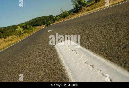 Molto distanti auto che si avvicinano a una strada asfaltata Foto Stock
