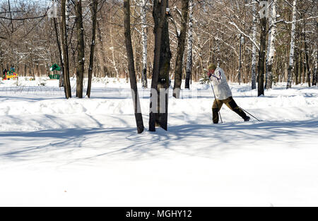 UFA, Russia 29marzo 2018 - uomo anziano cross country attraverso una pista forestale in nevicata utilizzando l'inverno sport per migliorare la sua salute mentre enjoyin Foto Stock