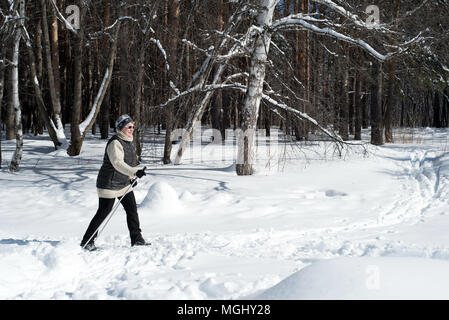 UFA, Russia 29marzo 2018 - Anziani donna che indossa gli sport invernali abbigliamento sci di fondo attraverso una pista forestale in nevicata utilizzando l'inverno sp Foto Stock