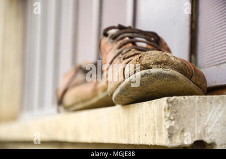 Fangoso e vecchie scarpe di fronte alla finestra del lavoratore scarpe, manodopera, indolenzimenti,fuoco selettivo Foto Stock