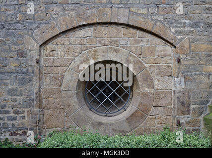 Antico muro di pietra arenaria con arco e bloccate finestra rotonda Foto Stock