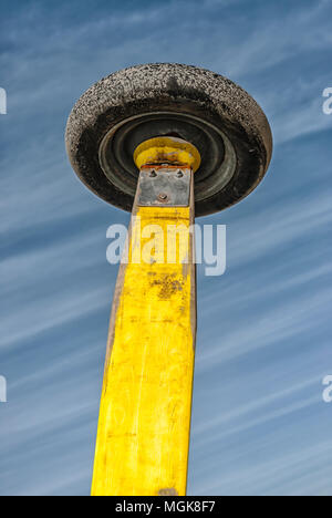 Una grande macchina pneumatico fissato ad un giallo spesso post in legno Foto Stock