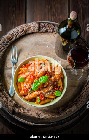Spicy penne bolognese servita con un bicchiere di vino rosso Foto Stock