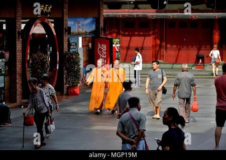 Due monaci buddisti in abiti dello zafferano attraversando a piedi il plaza fuori il Dente del Buddha reliquia tempio nella storica Chinatown, Singapore Foto Stock