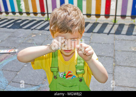 Carino ragazzo grida. Bambino piange su un parco giochi. Un bambino sfregato i suoi occhi. Un bambino con una allergia. Ragazzo triste grido al di fuori. Psicologia infantile e di emozioni. Portr Foto Stock