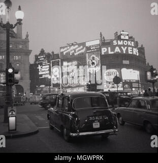 Anni sessanta, foto storiche di un taxi a Londra e un auto in attesa al semaforo presso la trafficata rotonda, Piccadilly Circus, Londra, Inghilterra, Regno Unito. Il famoso i cartelloni con la pubblicità di marchi come "Operatori" sigarette e coke può essere visto. Foto Stock