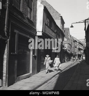 Degli anni Cinquanta, foto storiche di 'caos' in York, England, Regno Unito, un antico borgo medievale stretta viuzza acciottolata fiancheggiata con sovrastante antichi edifici con travi in legno e famoso per le macellerie (25 nel 1872) che utilizzate per il commercio lungo di essa nel XIX secolo. Infatti la parola 'shambles' è un antico termine per il macello. Foto Stock