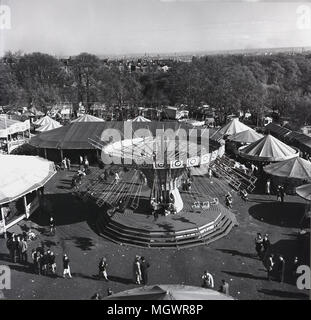 Degli anni Cinquanta, storico, una vista sulla fiera del divertimento al parco di Battersea, Londra, Inghilterra, con la grande giostra o merry-go-round nel centro. La fiera del divertimento è stato introdotto come parte del 1951 Festival di Bretagna celebrazioni nella sezione nord del parco e continuò fino ai primi anni settanta. Foto Stock