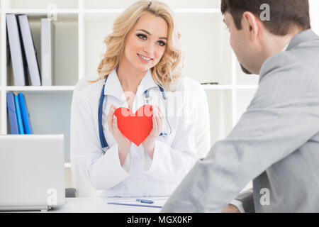 Medico mostra carta rossa cuore al paziente, cardio terapeuta consultazione Foto Stock