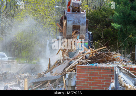Escavatore Demolizione di un vecchio edificio di casa per il nuovo progetto di costruzione. Foto Stock